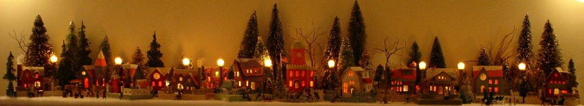 Antique Christmas cardboard house putz (village) on fireplace mantel at 
night 
(50K)