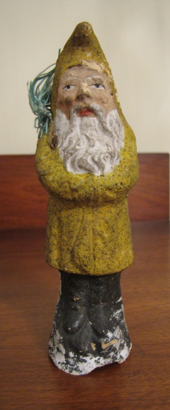 6-inch mustard yellow Belsnickle, hollow at base with a piece of straw showing in the composition.